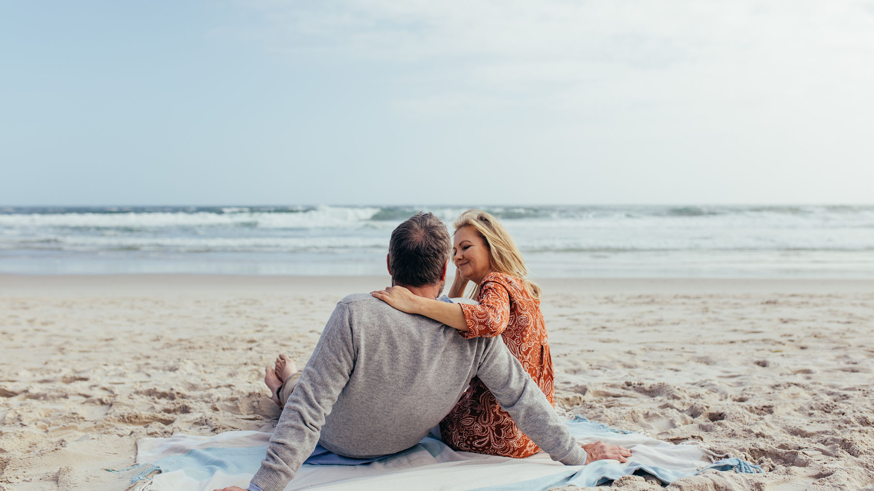 Couple sitting together on a beach, representing the peace of mind supported by organized tax filings and reliable accountancy services.