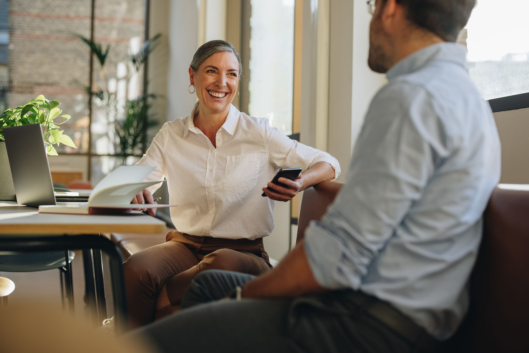 Two professionals meeting in a sunlit office, illustrating clear communication and organized documentation central to effective tax preparation and accountancy services.